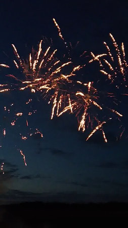 Fireworks in the night sky with clouds and silhouettes of peopleの写真素材