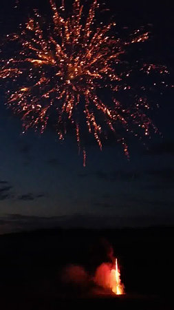 fireworks in the night sky with a red firework in the foregroundの写真素材