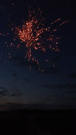 fireworks in the night sky with clouds and silhouettes of peopleの写真素材