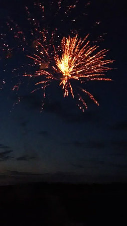 Colorful fireworks of various colors over night sky with clouds and sunの写真素材
