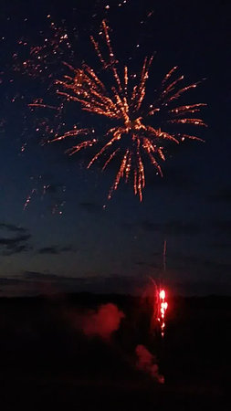 Fireworks in the night sky, with smoke and fire in the foregroundの写真素材