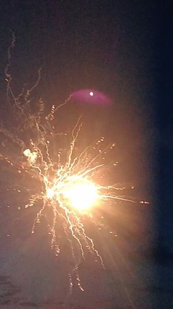 Fireworks in the night sky, with a moon in the backgroundの写真素材