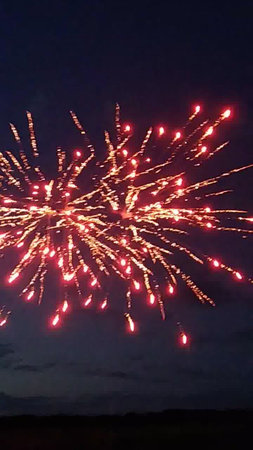 fireworks in the night sky with red and yellow sparks on a black backgroundの写真素材