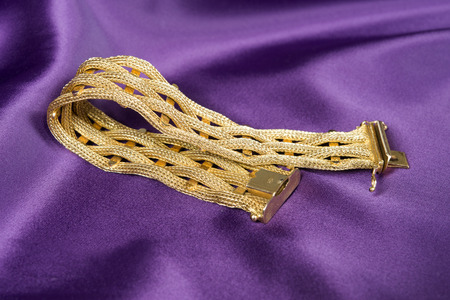 Gold bracelet isolated on purple satin background.の写真素材