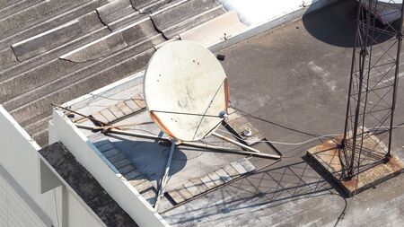 Old big telecommunication satellite dish on roof top of building.の写真素材