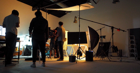 Behind the shooting production crew team and silhouette of camera and equipment in studio.の写真素材