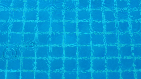 Rain drop falling on pool and have ripple shape and sun light reflection on surface for abstract...