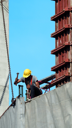 People working on construction site with yellow helmet and safty rope equipment and covering the building with grey color vinyl and blue sky.の写真素材