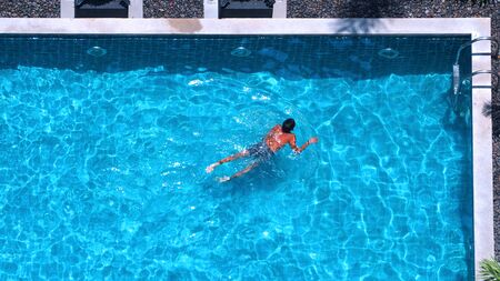 People swimming in the pool top view angle that have blue color water and sun light reflect on...