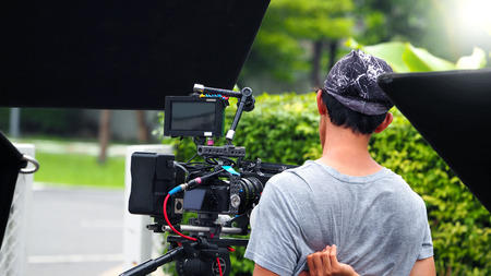 Behind the scenes of movie or video shooting production camera set and film crew at outdoor...