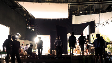 Silhouette of people working in big production studio for shooting or recording movie video by...