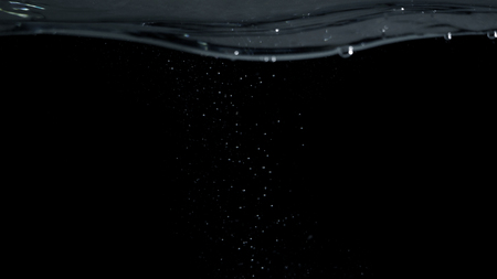 Soda water liquid splashing bubbles drop in black background represent sparkling and refreshingの写真素材
