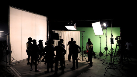 Behind the scenes of TV commercial movie film or video shooting production which crew team and camera man setting up green screen for chroma key technique in big studio.の写真素材