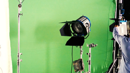Big studio LED spotlight for video movie or photo film production with green screen background for chroma key technique in post lab process and professional equipment such as tripod and others.の写真素材