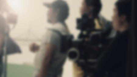 Blurred images of behind the scenes of filming or movie shooting or video production for online commercial and crew teams setting up light and prop and blue screen for next shot of camera recordingの写真素材