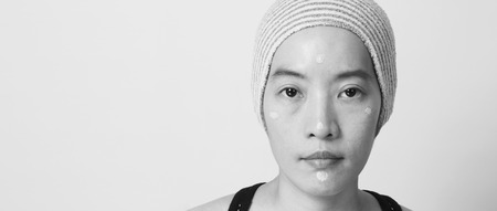 Asian girl or woman 40 years old beautiful face with japanese look making up by foundation liquid and cosmetic brush on sensitive skin for helping her complexion look flawless and no retouch.の写真素材