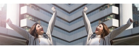 Beautiful asian business woman happy and cheerful or successful feeling with job which action like a winner by raise or lift up arms to the sky and shout yeah at outdoor city in summer season.の写真素材