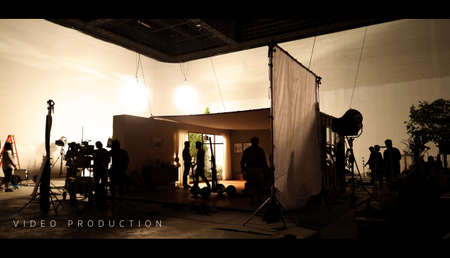 Behind the shooting video production and lighting set for filming which movie crew team working and silhouette shadow of camera and professional equipment in big studio for commercial advertising.の写真素材