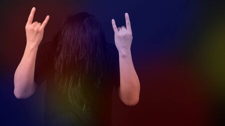 Rocker man long hair and making hand sign of rock and roll and shaking head with black color t-shirt...