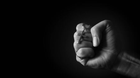 Close-up images of crucifix pendant and necklace in hand on black color background in studio which represent praying for god or jesus and thank gods for giving peaceful and faithful to peopleの写真素材