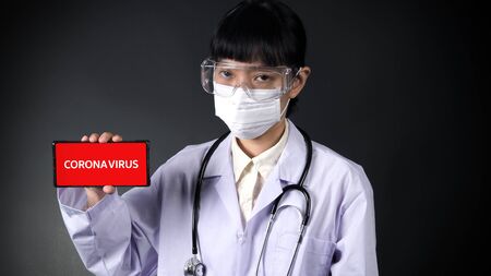 Young asian woman with mask holding up corona virus conceptの写真素材