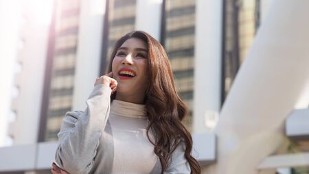 Asian business woman standing and finger up like a eureka action and feeling happy which represent have a brilliant idea, thoughtful, solve problem, imagination, inspiration or clever moment in workの写真素材