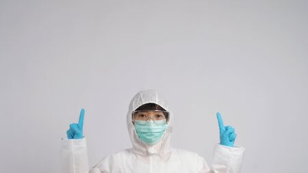 Asian doctor woman wear PPE suit or Personal Protective Equipment and medical mask and gloves which use for protect covid-19 virus pandemic and talking about quarantine for safetyの写真素材
