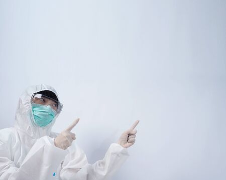 Doctor in PPE suit or Personal Protection Equipment point out to copy space and wearing white color medical rubber gloves and clear goggles glasses and green N95 mask to protect and fight pandemic virusの写真素材