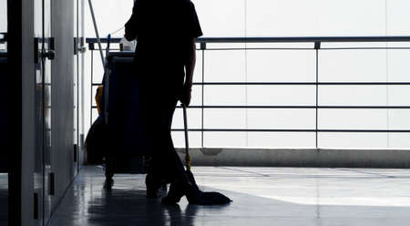 Silhoutte images of cleaning service man staff working around the terrace in building for hygenic place such as office and shopping store and he move back after finished his work.の写真素材