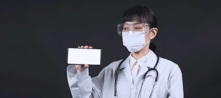 Middle aged of asian woman doctor showing mobile phone screen to communicate something. And she...