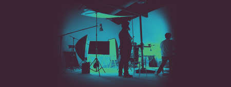 Two tone images of behind the scene of photo shooting production set up in the big studio. Professional crew team working and camera equipment in silhouette. And copy space added.の写真素材