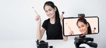 Asian teen woman sit in front of camera and live broadcasting as a beauty blogger influencer or...