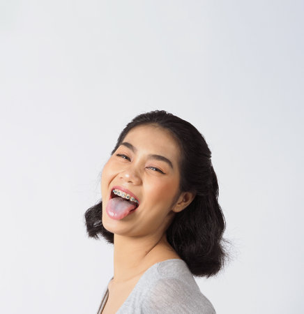 Dental brace beautiful girl smiling looking on a camera. white teeth with blue braces. Dental care. Asian teen woman smile with orthodontic accessories. Cosmetic dentistry, orthodontics treatment. white background studio.の写真素材