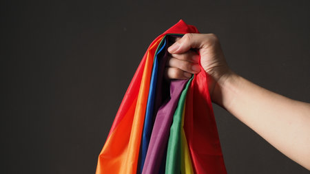 LGBTQ flag or Lesbian Gay Bi sexsual Transgender Queer or homosexsual pride Rainbow flag on black background. Represent hand symbol of freedom, peace, equality and love. LGBTQ conceptの写真素材