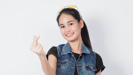 Gesture posing. Asian Young woman on white background cheerful and confident showing gestures. such as mini heart Okay Thumb up or point out. very happy amazed excited and surprised, Jacket jeans.の写真素材