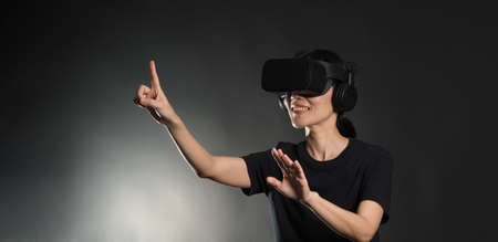 Girl with hands up wearing the VR headset goggles. Asian woman in glasses of virtual reality. The...