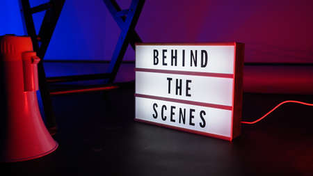 Behind the scenes letterboard text on Lightbox or Cinema Light box. Movie clapperboard megaphone and director chair beside. Background LED color change. static camera in video production studio.の写真素材