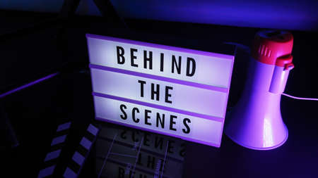 Behind the scenes letterboard text on Lightbox or Cinema Light box. Movie clapperboard megaphone and director chair beside. Background LED color change. static camera in video production studio.の写真素材