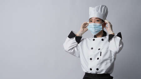 Chef wearing face protective medical mask or respirator for protection from virus disease. Food safety and coronavirus pandemic. chef posing gesture represent online ordering. food healthcare.の写真素材