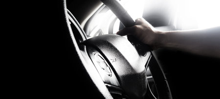 Steering wheel and man hand. Black leather modern car Interior close up. Hands on vehicle steering...