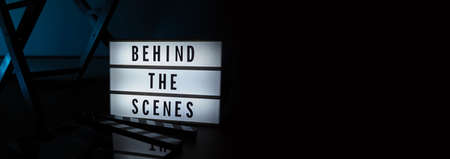 Behind the scenes letterboard text on Lightbox or Cinema Light box. Movie clapperboard megaphone and director chair beside. Background LED color change loop. static camera in video production studio.の写真素材