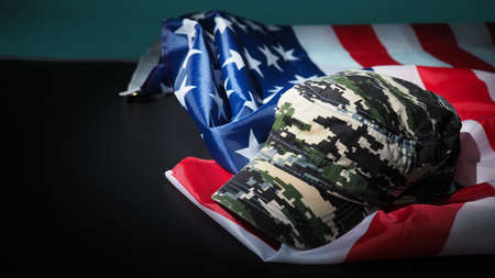 American flag and Military hat or bag. Top view angle. Soldier hat or helmet with national american flag on black background. Represent military concept by camouflage object and USA nation flag.の写真素材