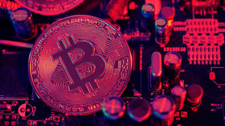 Bitcoin and semiconductor. Represent mining in Cryptocurrency cause global warming. Bitcoins on CPU board. Close-up Bitcoin with blue and pink light. circuit board with coin. Online asset concept.の写真素材