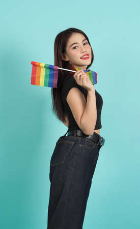 LGBTQ girl and pride flag. Sexy Lesbian girl and LGBTQ flag standing. blue green background. Asian LGBTQ woman with rainbow scarf on neck. Energetic cheerful. LGBTQ concept. LGBTQA+ Pride Month.の写真素材