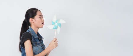 Teenage woman and paper windmill toys. Portrait teen with blue color paper wind wheel wood stick in...