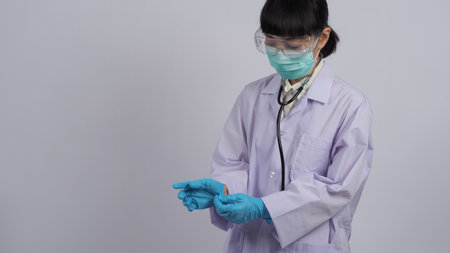 Wearing gloves. Asian doctor wear blue rubber nitrile hands glove. Doc with a mask putting on gloves. isolated white background copy space. Health care protection coronovirus pandemic concept.の写真素材