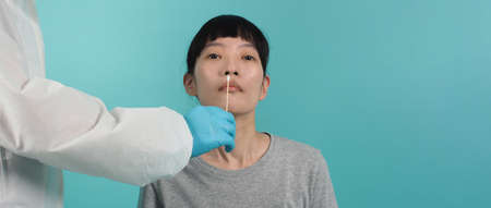 RT PCR test. woman with Covid 19 swab test. Coronavirus test during epidemic. Medic taking sample for virus testing. blue green background. Doctor in PPE suit swab testing. Virus Rapid Antigen Test.の写真素材