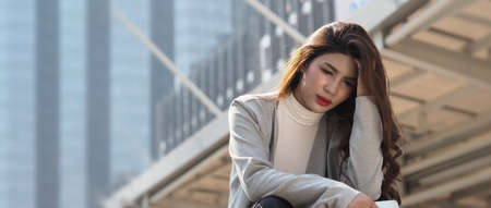 Lay off. Sacked. Fired business woman sitting on stairs of office building outside. Depressed young business woman unemployment due to coronavirus crisis. worry no job no money. Laid off got fired.の写真素材