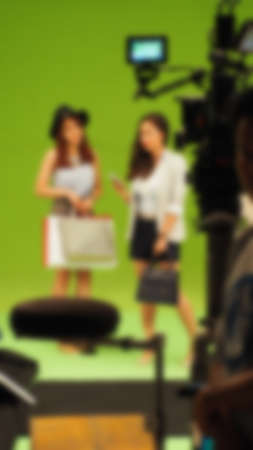 Blurry images of making TV commercial movie video in big green screen background. Film crew team...