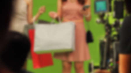 Blurry images of making TV commercial movie video in big green screen background. Film crew team working with actor. Recording by professional digital camera and lighting set. film behind the scenesの写真素材